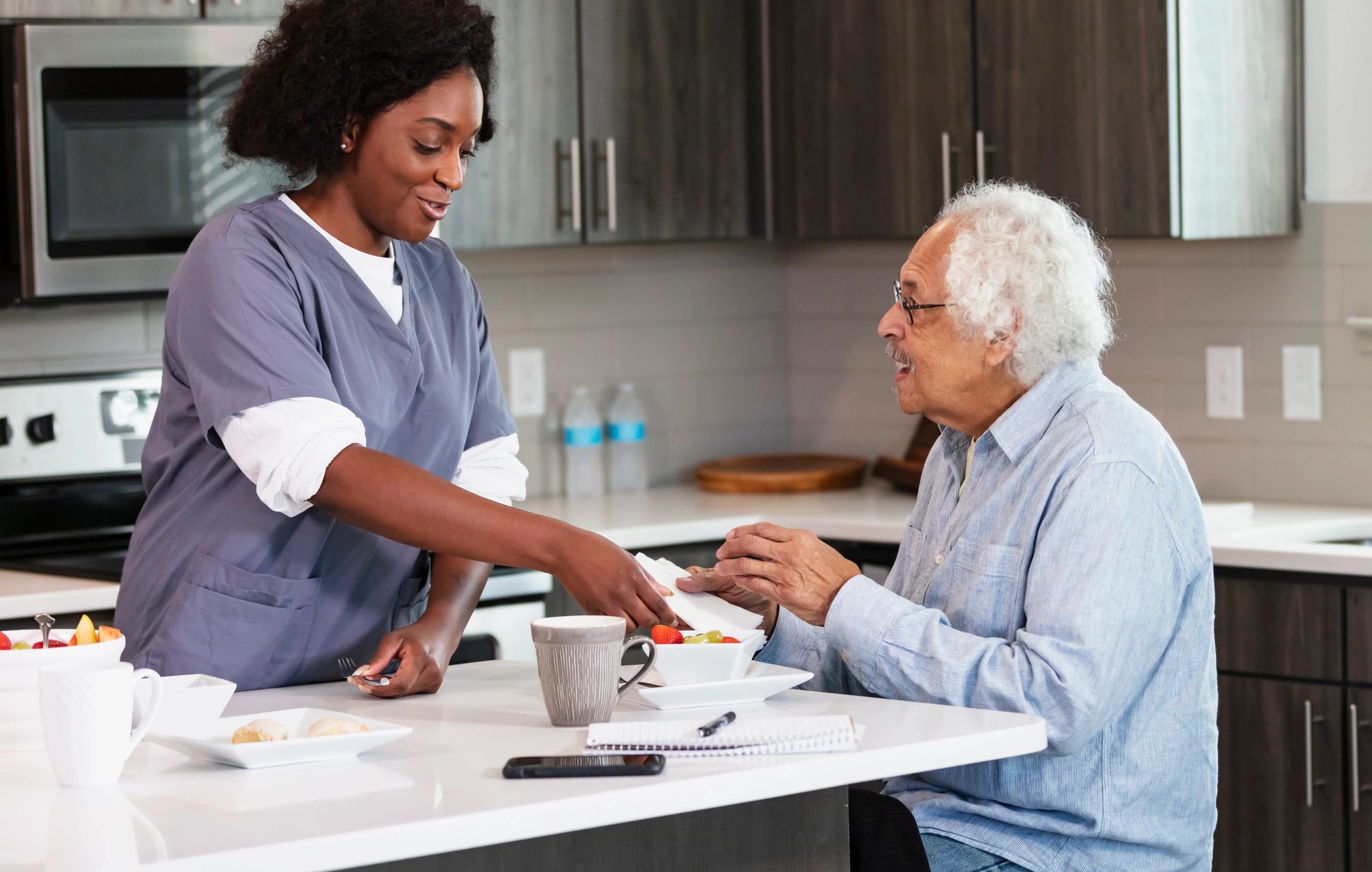 Home caregiver helping senior man in kitchen