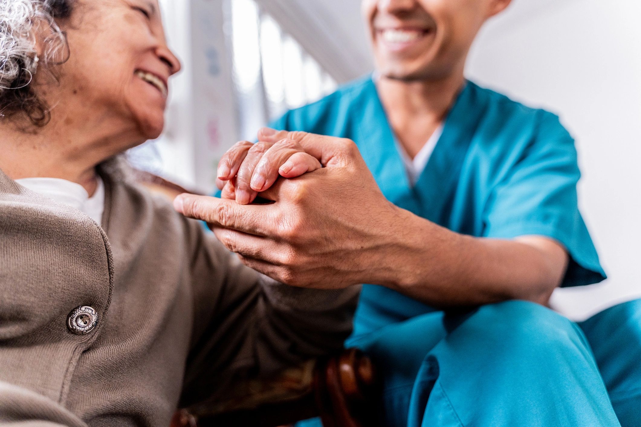 Senior woman holding caregiver hands at home