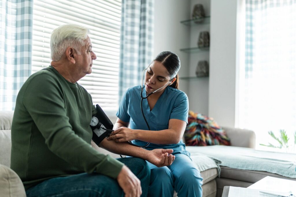 Home caregiver measuring the blood pressure of a senior man at home